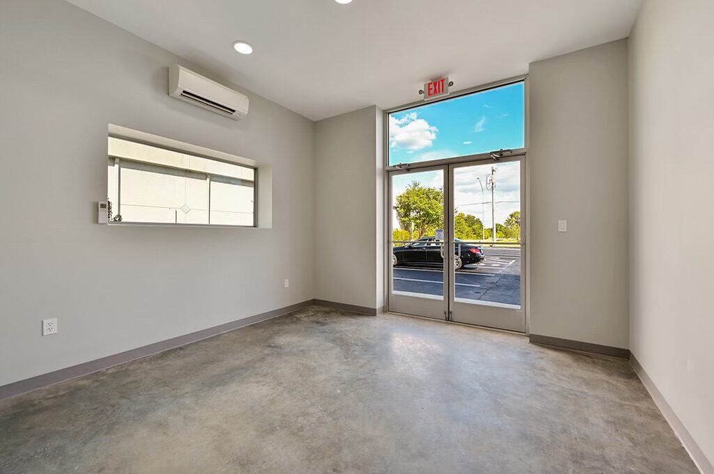 Finished office with a wall-mounted mini-split, clerestory window and glass exit doors to the parking lot