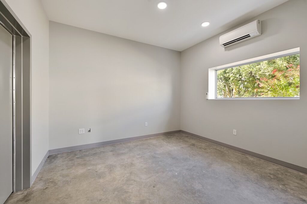 Office with polished concrete floor, mini-split and a clerestory window looking onto trees