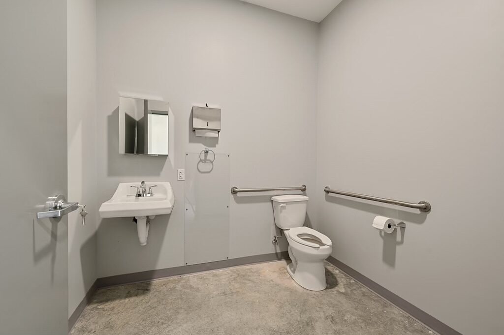 ADA-compliant restroom with grab bars, wall-hung sink and mirror