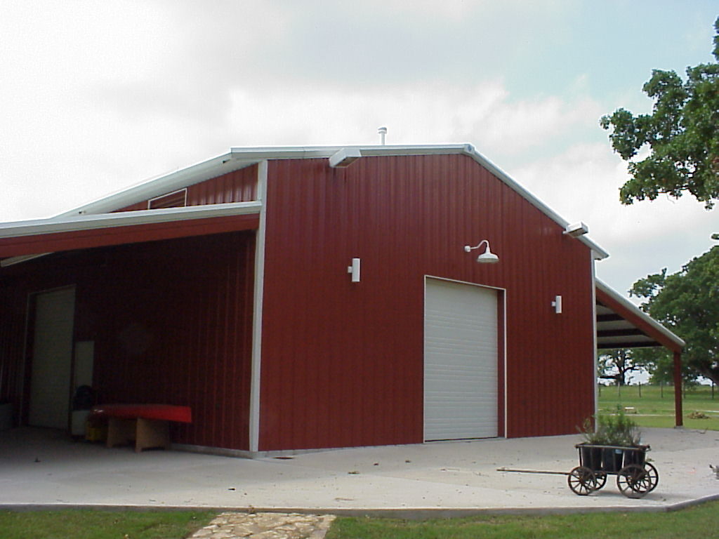 Three-quarter view of the party barn showing the open lean-to, sliding door and concrete slab