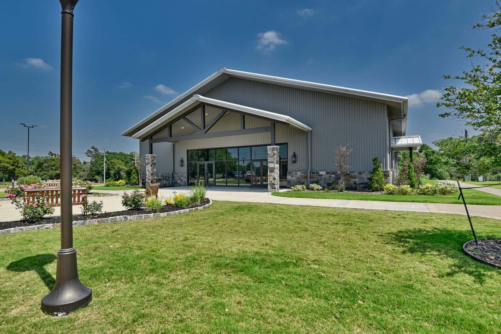 Entry elevation with the steel-truss gable, stone columns and glass entry doors