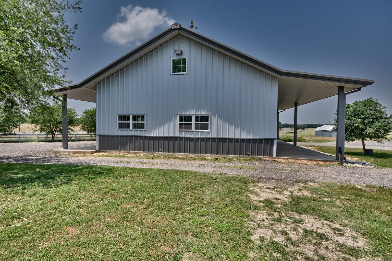 Gable end of a finished metal shop building with the porch roof carried around both sides