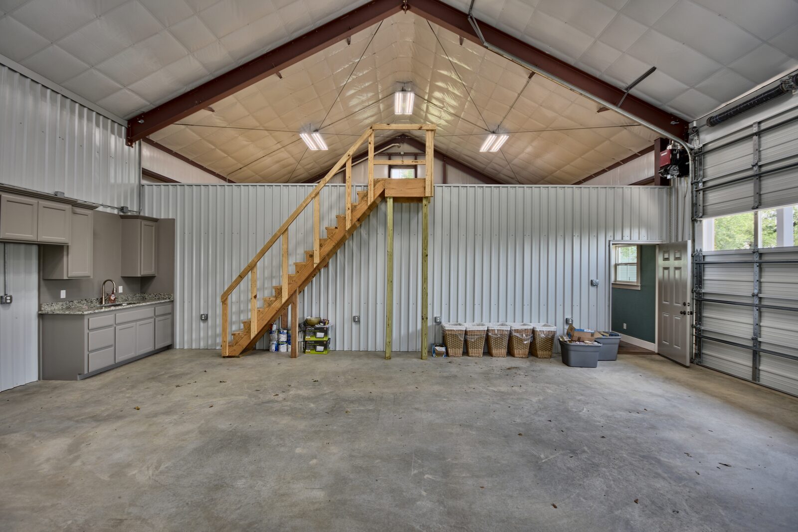 Inside the shop with a timber stair up to a loft, vaulted insulated ceiling and roll-up door