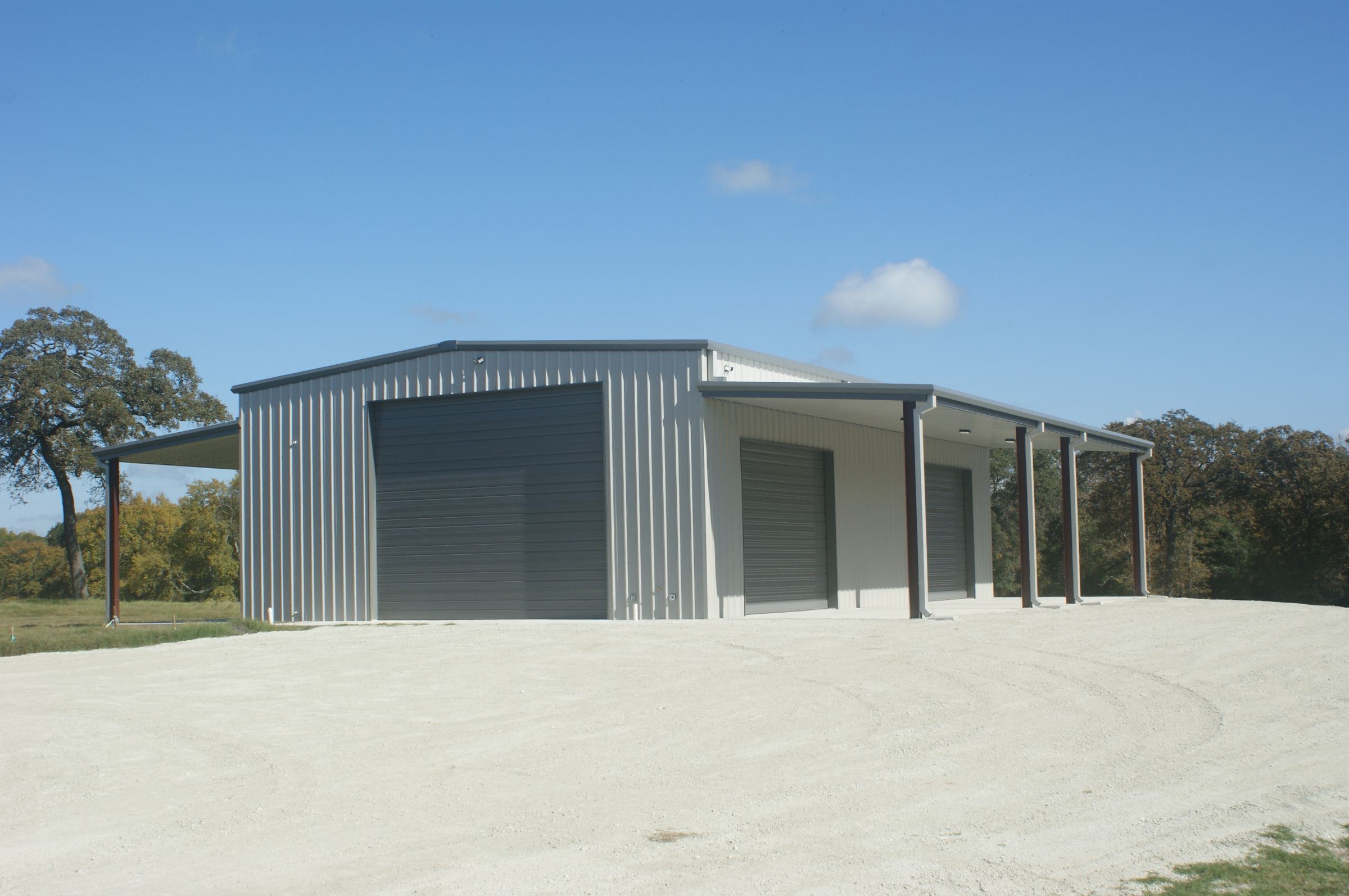 A Rhodes Building Systems metal shop building with lean-tos and roll-up doors